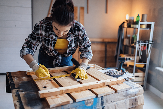 Una mujer trabaja en un proyecto de carpintería de madera en el garaje de una casa.  
