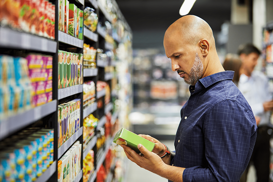 Un hombre lee la etiqueta de un producto en el pasillo de un supermercado.   