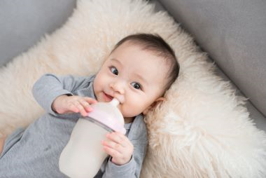 A smiling baby holding a bottle of milk