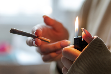A woman holding a lighter and a marijuana joint.