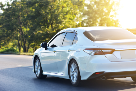A white compact vehicle on a road  