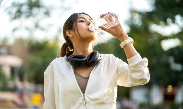 A woman drinking out of a plastic water bottle.