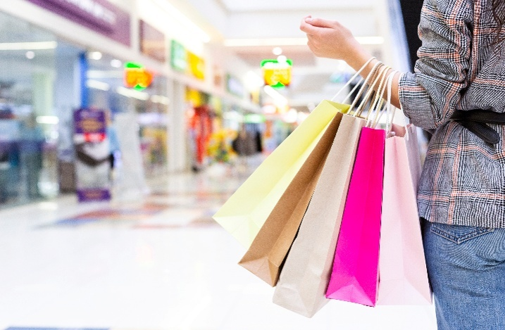 a woman holding multicolored shopping bags at a mall
