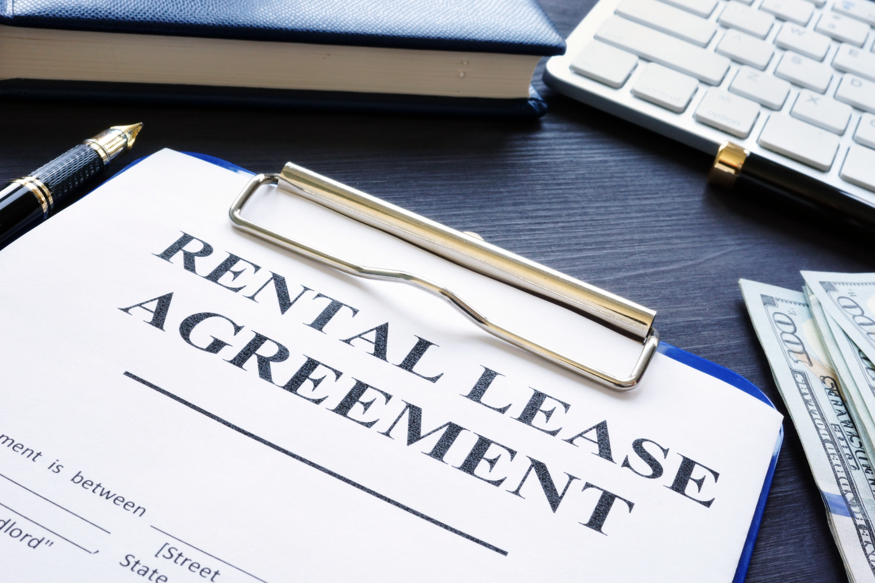 a clipboard with a paper that says “Rental Lease Agreement” at the top 