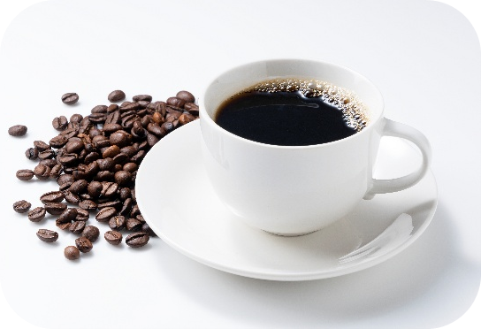 Una taza de cerámica blanca con café negro y granos de café esparcidos alrededor del platillo.